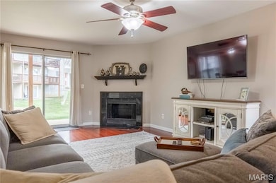 Living room with wood finished floors, a premium fireplace, and a ceiling fan