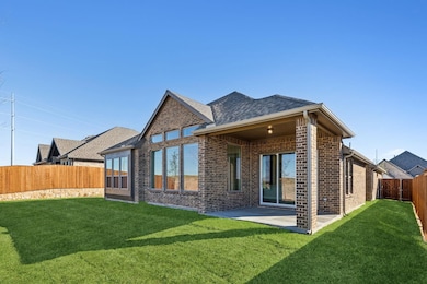 Back of property with a fenced backyard, brick siding, and a patio area
