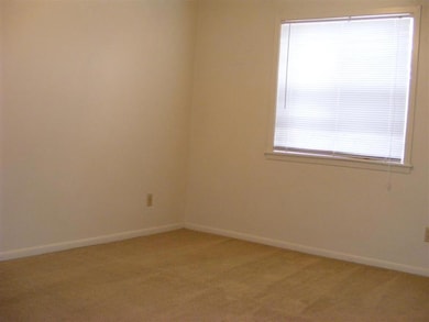 Empty room with light colored carpet and baseboard