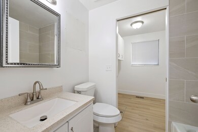 Full bath with vanity, light wood-style floors, and a tub to relax in