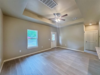 Bright living area featuring ceiling with fan, neutral walls, and wood-style flooring.Note: Photos are of a similar home by the builder.