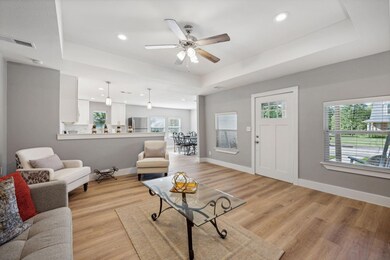 Living room featuring ceiling fan, a raised ceilin
