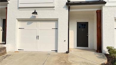 Doorway to property featuring brick siding, a garage, and driveway