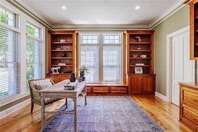 Custom built cherry office space has oversized windows, gleaming hardwoods and custom built-ins. There is also a pocket door that leads to and additional space that was planned to extend the powder room on the other size to a full bathroom if desired.