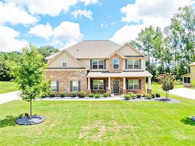 Craftsman-style home featuring board and batten siding, covered porch, a front lawn, and brick siding