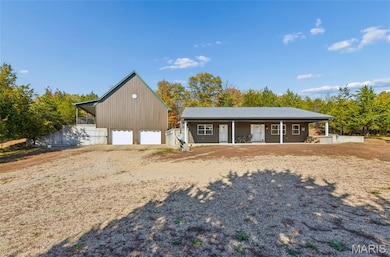 View of front of home featuring covered porch, an outdoor structure, driveway, and a garage