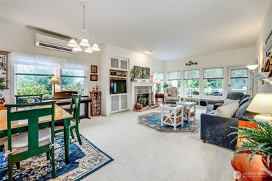 Photo from the entry. Living room and dining area. Notice the fireplace and the energy efficient ductless heat pump.  Lots of windows for light.