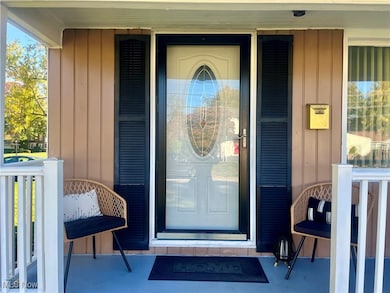 View of exterior entry with board and batten siding and a porch