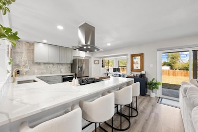 Kitchen featuring light stone countertops, a kitchen breakfast bar, a peninsula, gray cabinetry, and light wood-type flooring