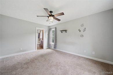 Carpeted spare room featuring a ceiling fan and ba