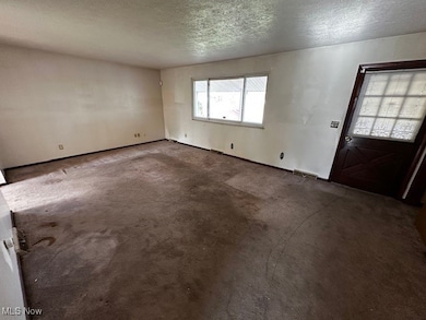 Entryway with a textured ceiling and dark colored carpet