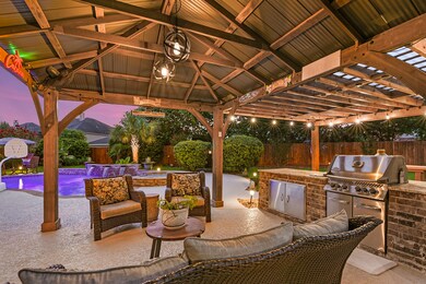 This backyard is perfect for entertaining, featuring an oversized covered patio with an outdoor kitchen, cool deck concrete flooring, a ceiling fan, and lighting. It also includes a heated pool and spa, along with ample green space to accommodate all your needs.