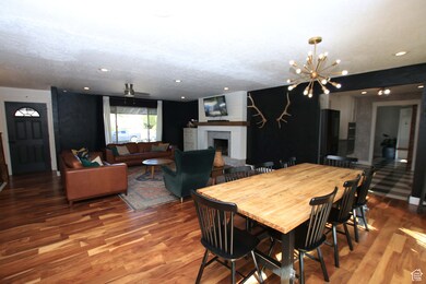 Dining area with a brick fireplace, wood finished floors, a chandelier, recessed lighting, and ceiling fan