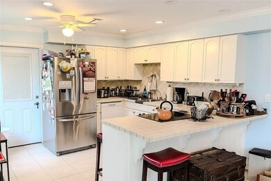Kitchen with tile countertops, stainless steel fridge, crown molding, a breakfast bar area, and light tile patterned floors