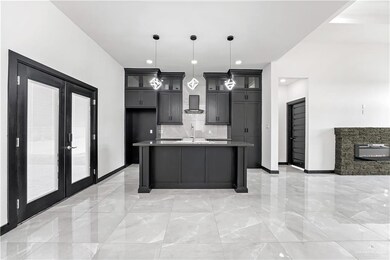 Kitchen with french doors, decorative backsplash, hanging light fixtures, a center island with sink, and wall chimney exhaust hood