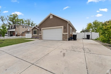 Ranch-style home featuring a gate, stone siding, concrete driveway, an attached garage, and stucco siding