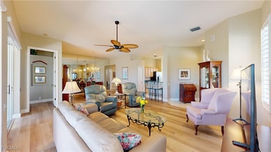 Living area featuring ceiling fan, light wood finished floors, and a chandelier