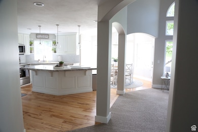 Kitchen featuring stainless steel appliances, arched walkways, backsplash, open shelves, and white cabinets