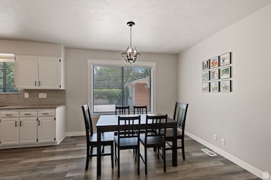 Dining room with healthy amount of natural light, dark wood finished floors, a textured ceiling, and a chandelier