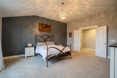 Carpeted bedroom with a notable chandelier and vaulted ceiling