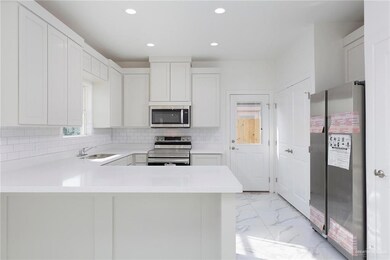 Kitchen with light countertops, marble finish floor, a sink, and appliances with stainless steel finishes