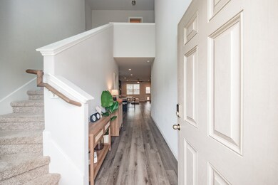  It features carpeted stairs to the left, stylish wood flooring, and a neutral color scheme that enhances the sense of space.