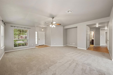 Unfurnished living room with carpet, ceiling fan,