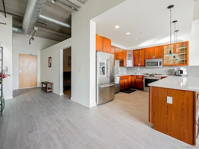 Kitchen featuring glass insert cabinets, stainless steel appliances, backsplash, light wood-style floors, and pendant lighting