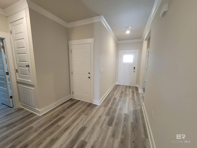 Entryway with ornamental molding and wood finished floors
