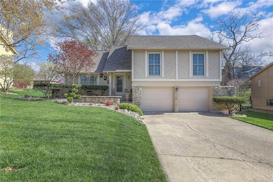 Split level home with driveway, stone siding, a front yard, a garage, and a shingled roof
