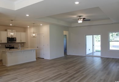 Kitchen with a raised ceiling, open floor plan, hanging light fixtures, white cabinetry, and recessed lighting