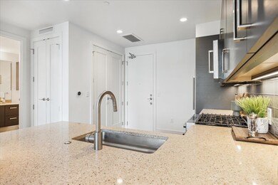 Kitchen with a sink, light stone counters, recess