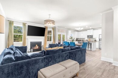 Living area featuring a chandelier, crown molding, light wood finished floors, a lit fireplace, and recessed lighting