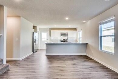 Kitchen featuring white cabinetry, light hardwood / wood-style floors, kitchen peninsula, stainless steel appliances, and light stone countertops