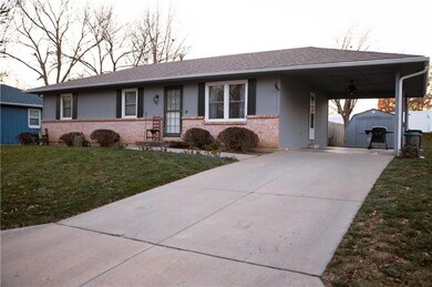 Ranch-style house featuring a carport, a shed, and a front lawn