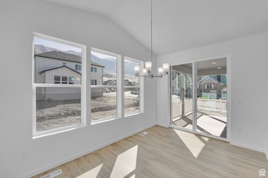 Unfurnished dining area with a mountain view, light wood-type flooring, lofted ceiling, a residential view, and a chandelier