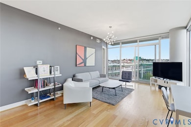 Living room with expansive windows, light wood-style floors, and a chandelier
