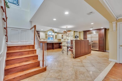 Kitchen with decorative light fixtures, a kitchen breakfast bar, stainless steel built in fridge, a kitchen island, and glass insert cabinets