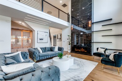 Living room with wood finished floors, a towering ceiling, and a fireplace