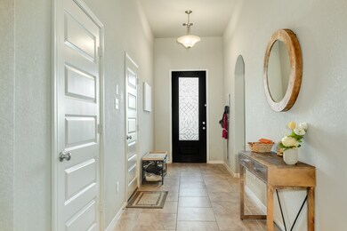 Welcoming entryway with a decorative glass front door. The tiled flooring, neutral color palette and high ceilings enhances the spacious feel.