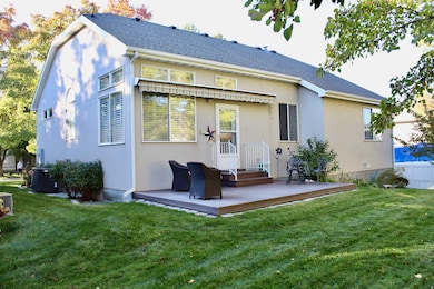 Rear view of property featuring a deck, stucco siding, and a shingled roof