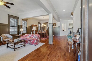 Living area with a chandelier, wood finished floors, wainscoting, ceiling fan, and stairway