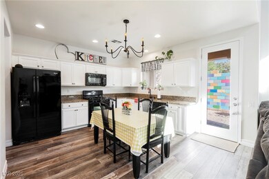 Kitchen with black appliances, white cabinetry, recessed lighting, and wood-style flooring