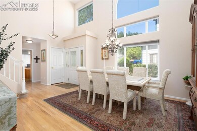 Dining area featuring light wood-style floors, stairway, a chandelier, a towering ceiling, and baseboards
