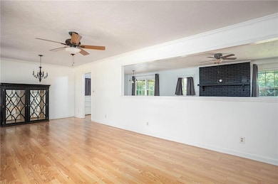 Spare room with a ceiling fan, wood finished floors, a chandelier, a fireplace, and a textured ceiling