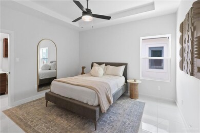 Bedroom with ceiling fan, a raised ceiling, and light tile patterned floors