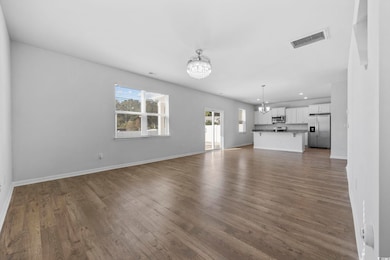 Unfurnished living room with a chandelier, dark wood-style flooring, and recessed lighting