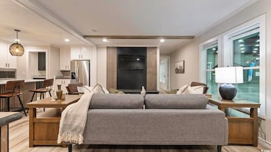 Living room with light wood-type flooring, recessed lighting, beamed ceiling, and ornamental molding