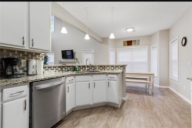 Kitchen featuring a peninsula, backsplash, white c