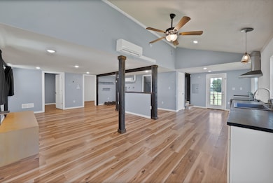 Kitchen with light wood finished floors, recessed lighting, open floor plan, dark countertops, and ventilation hood